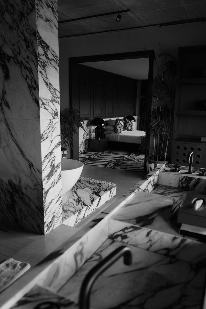 Black and white photo of a stylish marble bathroom with a luxurious bathtub and contemporary decor.